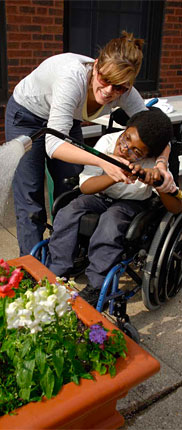 PHOTO: A young man in a wheelchair waters a raised planter.