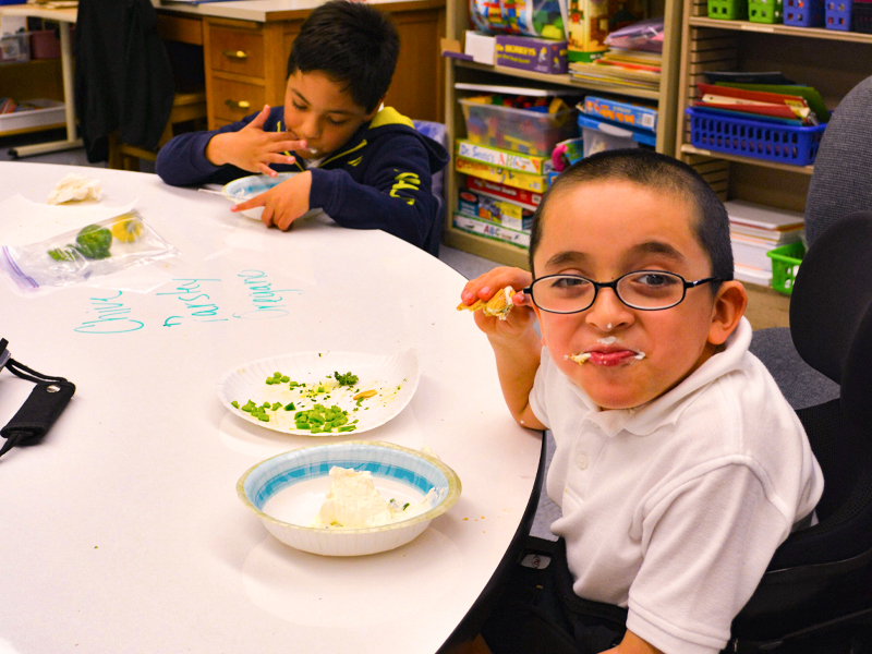 A student enjoys his homemade herb dip with garden cucumbers and peppers for dipping.