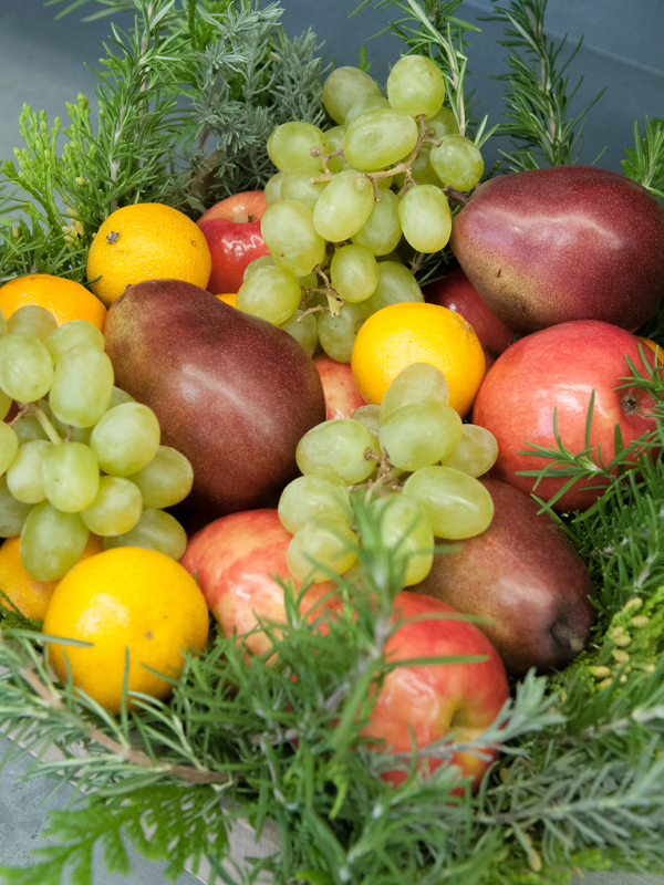 Fruits are arranged on a bed of fragrant rosemary for this simple seasonal basket.